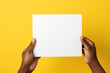 Person holding a white piece of paper in their hands on a yellow background 
