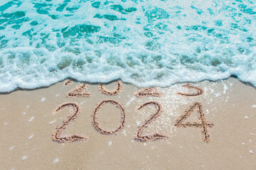 Wall Mural - message year 2023 replaced by 2024 written on beach sand background. good bye 2023 hello to 2024 hap