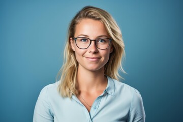 Wall Mural - Portrait of a beautiful young businesswoman wearing glasses over blue background.