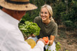 © cherryandbees - Young woman giving lettuce and tomato to her grandfather.