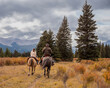 A man and woman horseback riders make their way along a trail in the Ya Ha Tinda Ranch in Alberta, Canada during autumn