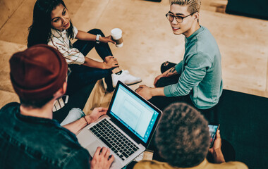 Top view of multiracial crew of students discussing ideas for coursework sitting in campus smiling