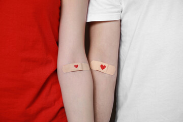 Sticker - Blood donation concept. Couple with adhesive plasters on arms, closeup