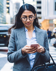 Wall Mural - Young ethnic female using smartphone outdoors