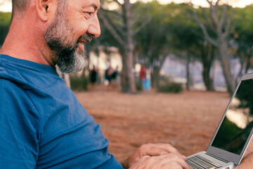 Wall Mural - One modern adult man using and working on laptop at the park. Concept of smart working and freelance digital nomad small business online free lifestyle. People with computer outdoor leisure activity