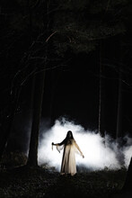 Ghost with knife standing in front of smoke in forest at night