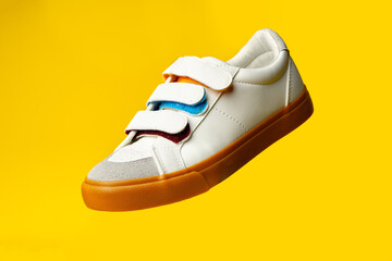 Sticker - White leather sneakers with fasteners on yellow background