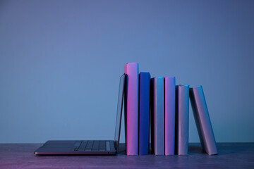 Stack of books and laptop on gray background