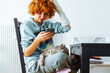 Portrait teenage girl with red hair, cast on arm and domestic cat at home