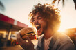 Close up photo of man eating tasty burger with warm sun lighting on background