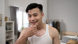 © PRPicturesProduction - smiling Korean male looking at camera like mirror satisfied with his perfect facial skin while getting ready for the day at home.