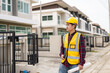 © ArLawKa - Young Asian engineer inspects architecture, construction project concept, young professional engineer in helmet and blueprint paper at house construction site.