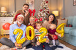 Family holding giant balloons shaped as numbers 2024 while having New Year party