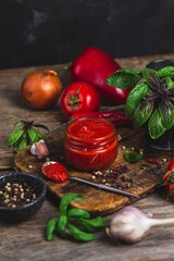 Wall Mural - Ketchup in a jar. Tomato sauce on a dark background