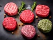 Raw beef patties with rosemary and spices on black background
