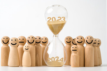Wall Mural - hourglass with brown sand for change 2023 to 2024 year among smile wooden figures , countdown and pr