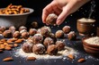 hand sprinkling crushed almonds on date and nut balls