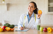© Prostock-studio - Happy female nutrition adviser holding orange fruit, making meal plan for client and smiling at camera