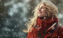 young woman with blonde hair and red coat enjoing snow fall in sun light