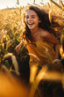 canvas print picture - Ein Mädchen läuft lachend im spätsommerliche Abendfeld durchs Kornfeld. Bekleidet mit einem Sommerkleid. Geeignet für Kindermode.