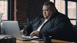 © JKLoma - big size business man, fat man note and check on financial paper at working table.
