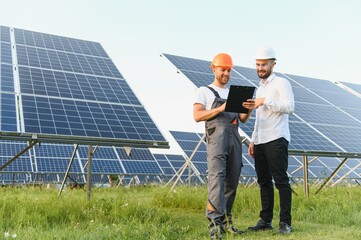 Businessman and worker near solar energy batteries. Business client showing photovoltaic detail to foreman. Two men making deal.