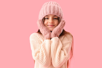 Wall Mural - Cute little girl in winter clothes on pink background
