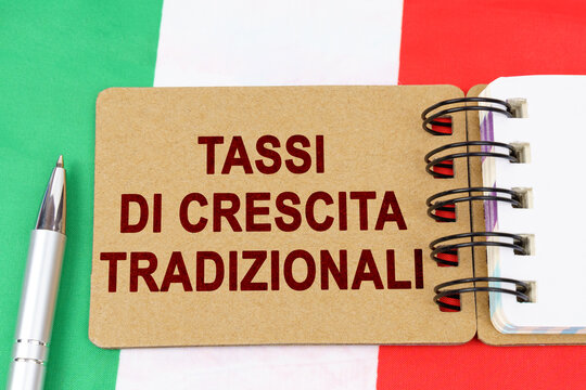 On the flag of Italy lies a pen and a notebook with the inscription - traditional growth rates