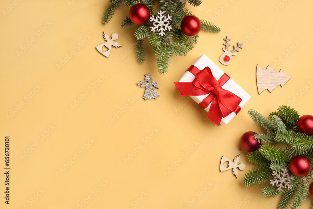Christmas tree branches with decorations and gift box on yellow background