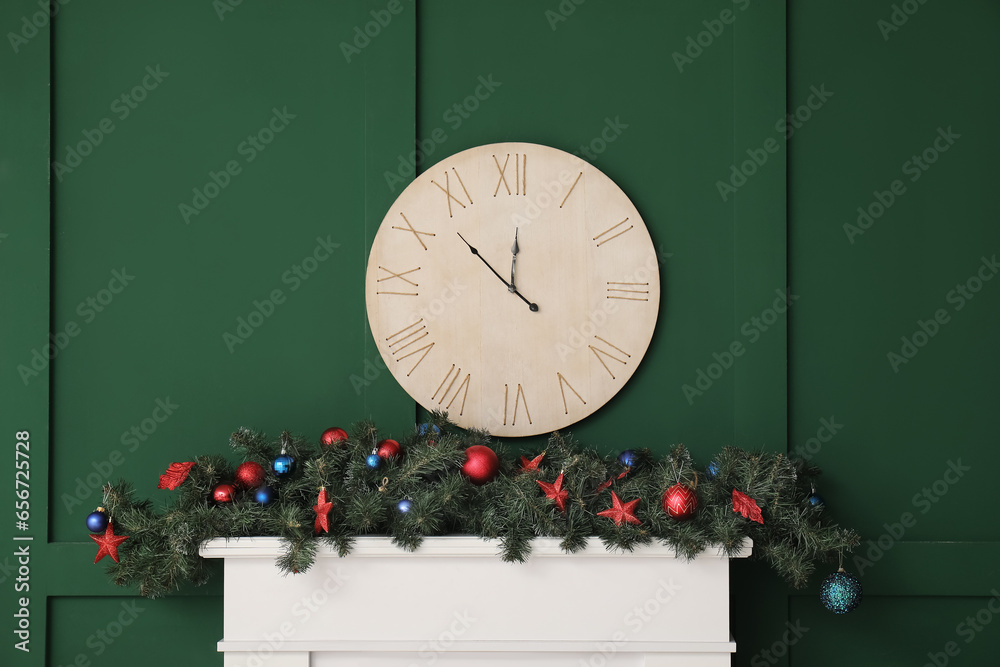 Mantelpiece with Christmas decor and clock on green wall in room