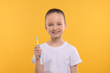 Wall Mural - Happy girl holding toothbrush on yellow background