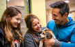 Young adorable family adopting a dog from a shelter, happily smiling while getting to know the small dog