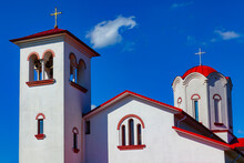 Red And White Church Against Blue Sky With Clouds. Religious Architecture