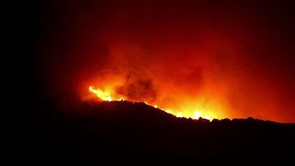 Wall Mural - Flaming wild fire inferno, rolling over mountains, during nighttime - Time-Lapse