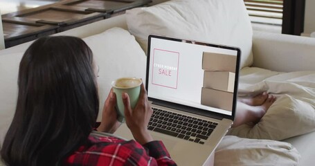 Poster - Biracial woman on couch with coffee, using laptop for online shopping, slow motion