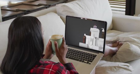 Poster - Biracial woman using laptop at home for online shopping, slow motion