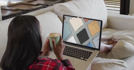 Poster - Biracial woman using laptop at home for online shopping, slow motion