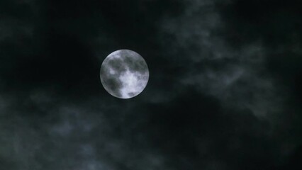 Wall Mural - clouds moving past a bright full moon in the night sky. mysterious horror film atmosphere. close-up