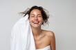 Attractive woman face in towel. Beauty portrait of a smiling attractive half naked woman. Skin care and treatment, spa, natural beauty and cosmetology concept.