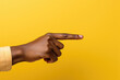 © vefimov - Person is pointing at something on vibrant yellow background. This image can be used to illustrate communication, direction, or decision-making concepts.