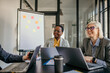 © La Famiglia - A diverse ensemble of coworkers gathered in a boardroom, actively discussing strategies and sharing ideas for a successful business outcome.