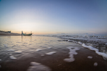 Wall Mural - Silhouettes of fishermen on the beach pushing wooden boats out to sea to fish wooden boats on Ho Coc Vung Tau beach