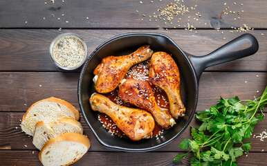 Wall Mural - Roasted chicken legs with potatoes and bread on the wooden background. 