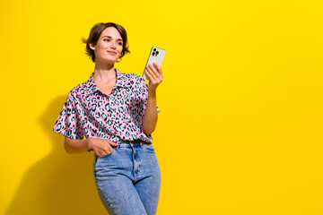 Wall Mural - Portrait of lovely positive person use smart phone texting empty space ad isolated on yellow color background