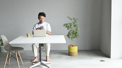 Wall Mural - Man looking at and tapping phone in white room Wide angle