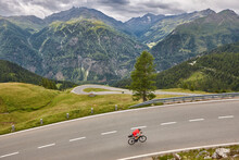 Cyclist in alpine serpentine mountain road. Highlight route in Austria