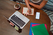 © Westend61 - Businesswoman writing on diary by laptop at table in cafe