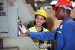 © offsuperphoto - worker or engineer training and teaching how to use machine control with coworker in factory