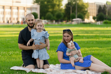 Wall Mural - mom and dad playing with their kids on the lawn outdoors, spend time together