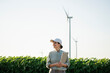 © Westend61 - Smiling agronomist holding laptop at field with wind turbines in background
